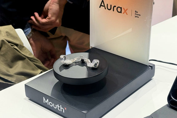 MouthX hands-free controller on display at an event booth, showcased on a stand with Aurax branding in the background.