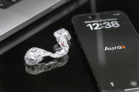 Dispositivo MouthX junto a un smartphone sobre superficie negra.